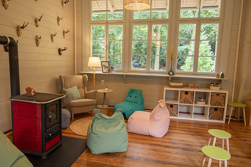 Kaminofen-Ecke in Waldschule mit Lesesessel, Lampe und Sitzsäcken