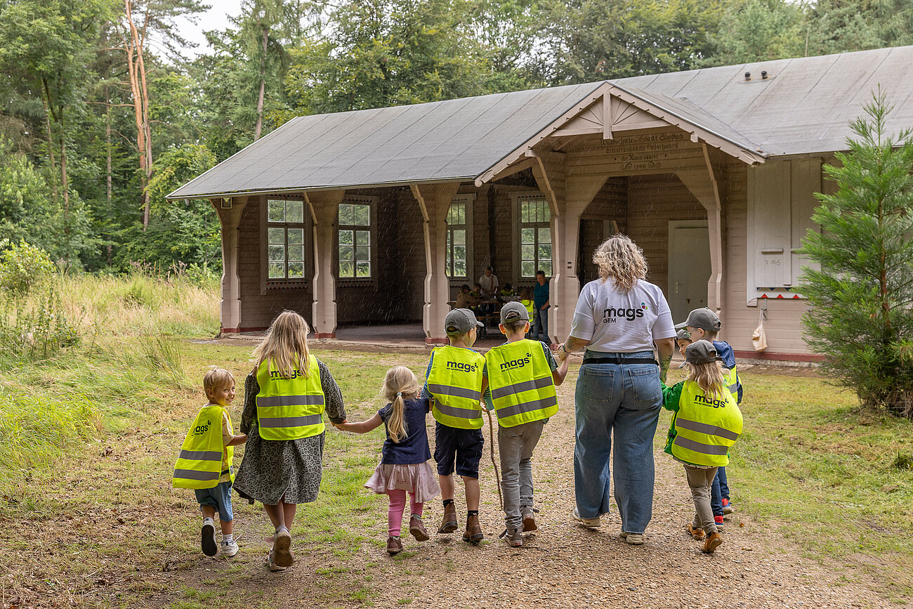 Das Foto zeigt 7 Kinder und eine Betreuerin, die auf die Hardter Waldschule zugehen.